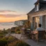 Amis profitant de la terrasse d’un gîte à Petit-Caux face à la mer au coucher du soleil