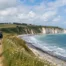 Deux randonneurs marchant sur un sentier côtier au-dessus des falaises blanches et de la mer près de Petit-Caux