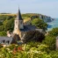 Vue lumineuse du village de Saint-Martin-en-Campagne entouré de verdure avec la mer et les falaises en arrière-plan